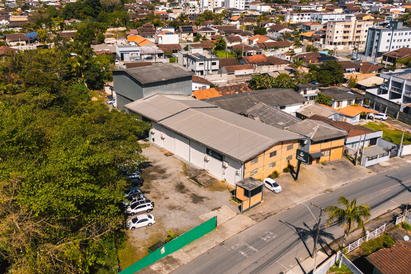 A igreja vista de cima, entre as árvores do terreno vizinho e as casas do Itaum