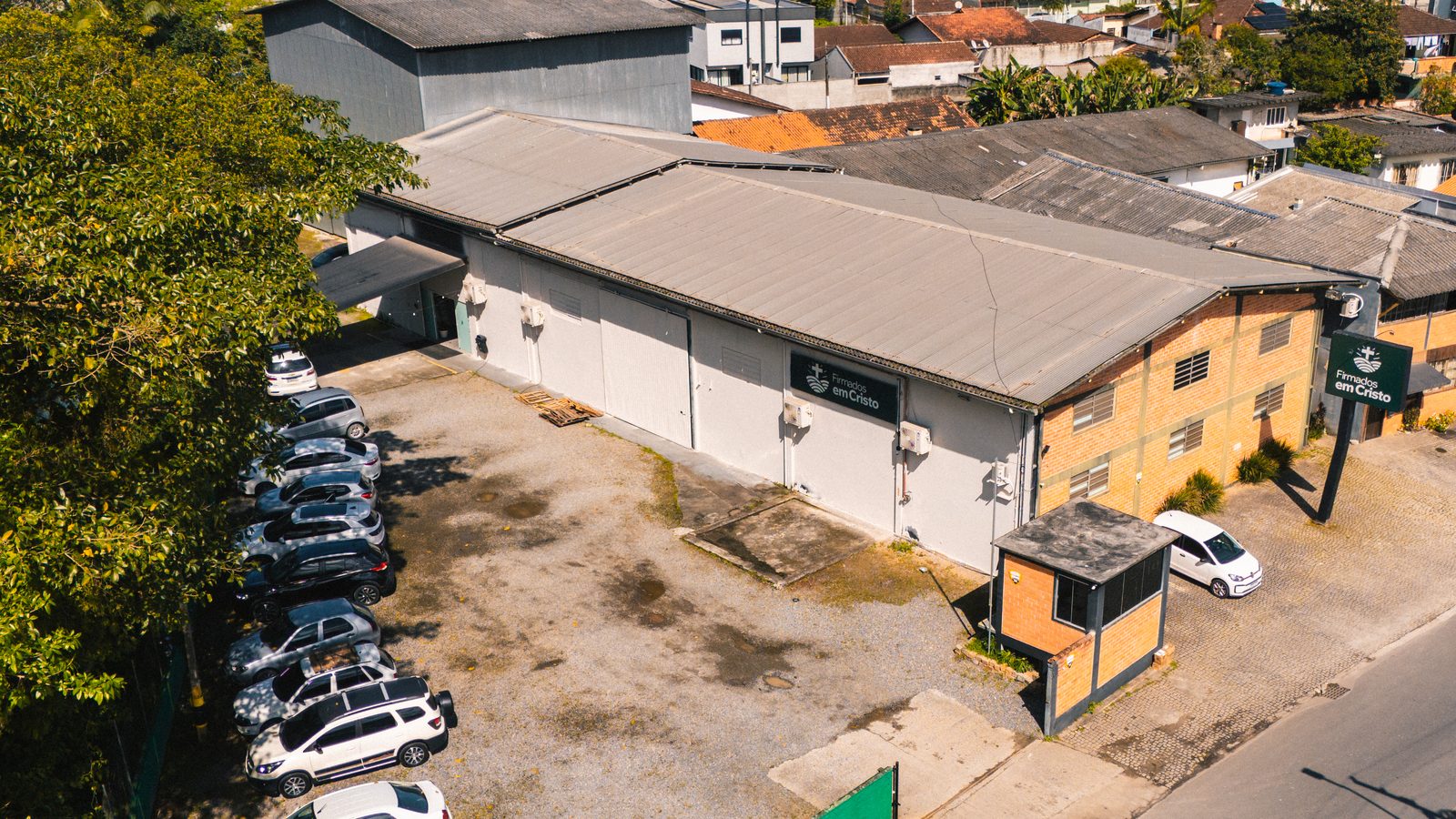 Vista aérea do prédio da Igreja Firmados em Cristo na Rua Botafogo, com o pátio de estacionamento e o bairro Itaum ao redor